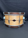 Wooden snare drum with metal hardware on a black background