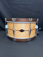 Wooden snare drum with metal hardware on a black background