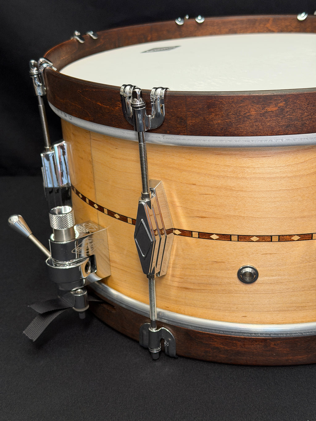 Close-up of a banjo with a focus on the head and tuning pegs against a dark background.