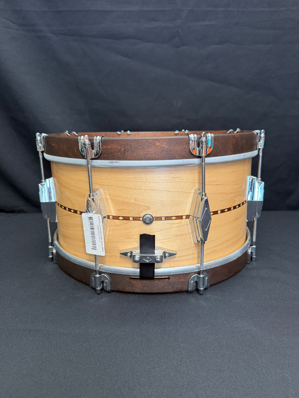 Wooden snare drum with metal hardware on a dark background