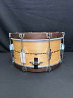 Wooden snare drum with metal hardware on a dark background