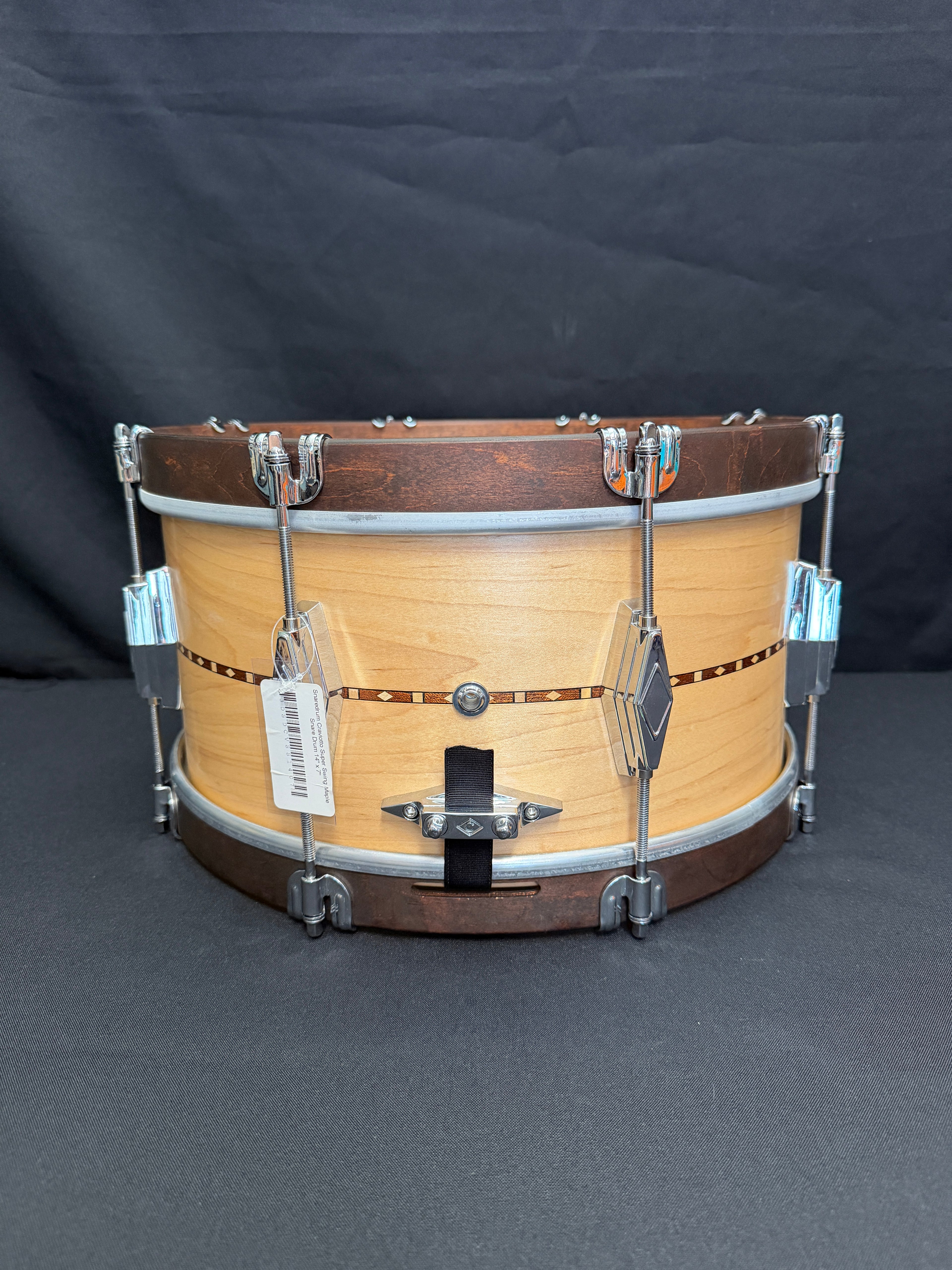 Wooden snare drum with metal hardware on a dark background